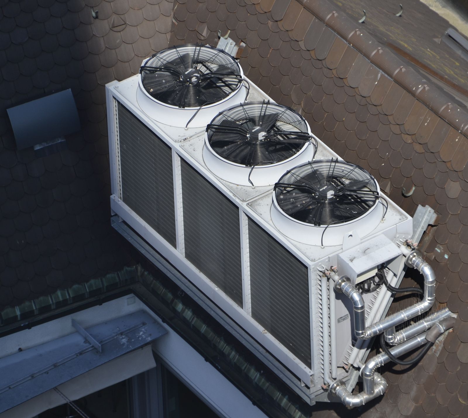 Large commercial multi-fan air conditioning condenser unit mounted on a roof