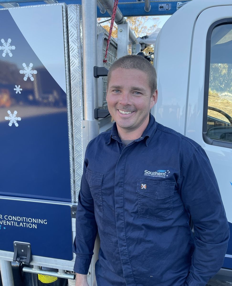 Southern Aircon & Refrigeration technician in a company shirt beside the service van