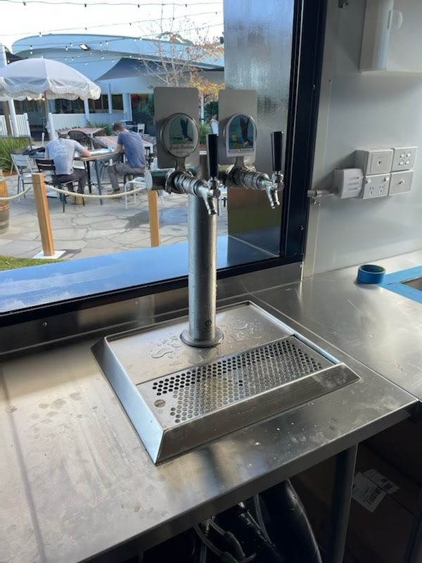 Stainless steel beverage tap and drip tray at a bar counter